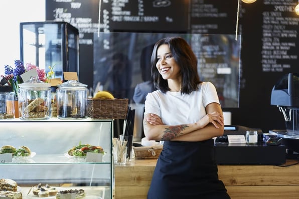 A smiling small business owner leaning against a counter