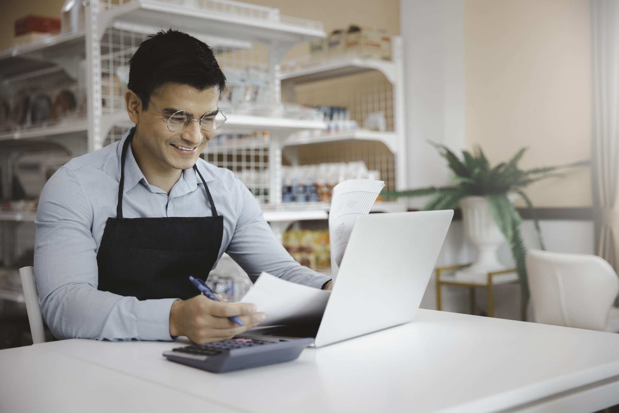 Entrepreneur male business owner in eyeglasses using computer laptop working in grocery shop store